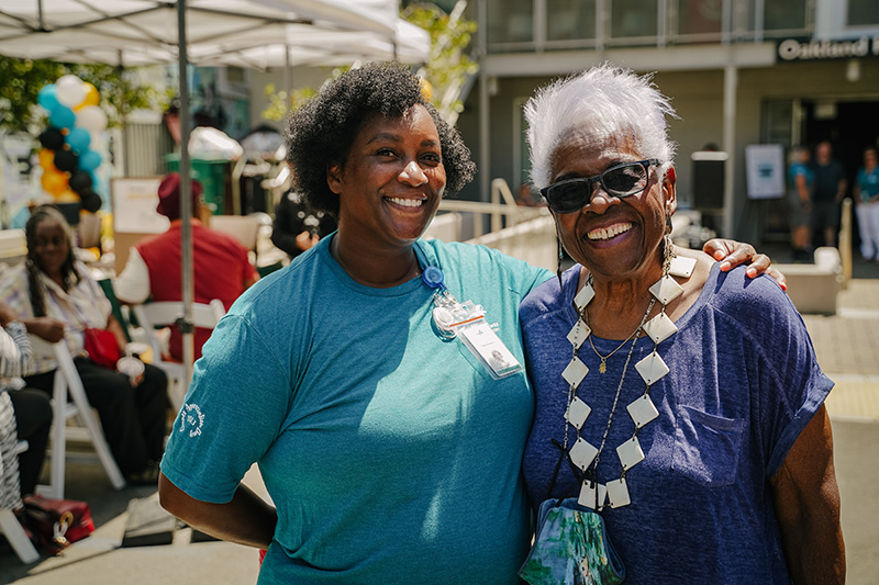 Two smiling women outside at an event.