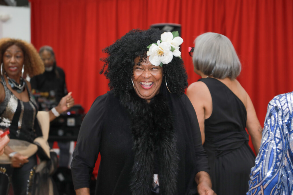 Older adults smile and enjoy the Oakland Housing Authority Senior Splendor event in a decorated community hall.