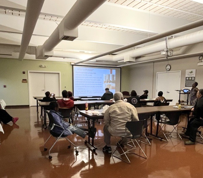 Alt Text: OHA residents attend an estate planning workshop, seated at tables facing a presentation screen.