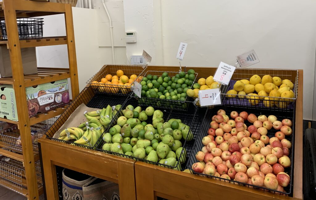 Display of fresh produce, including apples, pears, bananas, lemons, limes, and oranges, at an Oakland Housing Authority food distribution site.