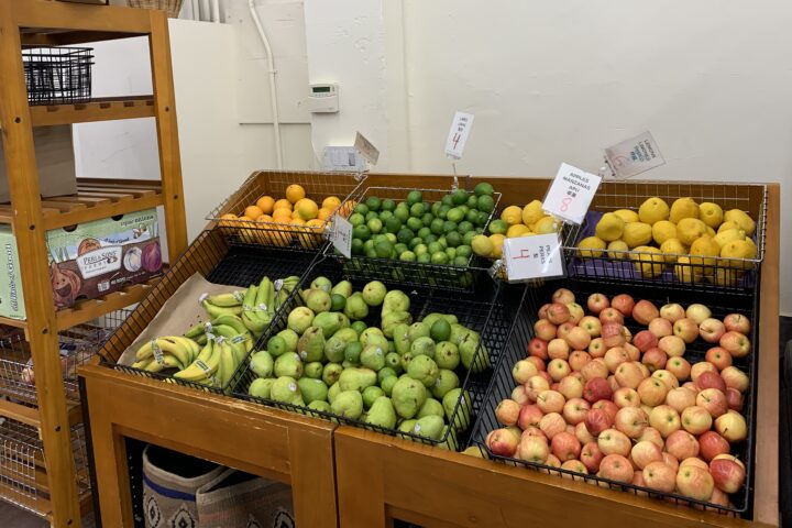Display of fresh produce, including apples, pears, bananas, lemons, limes, and oranges, at an Oakland Housing Authority food distribution site.