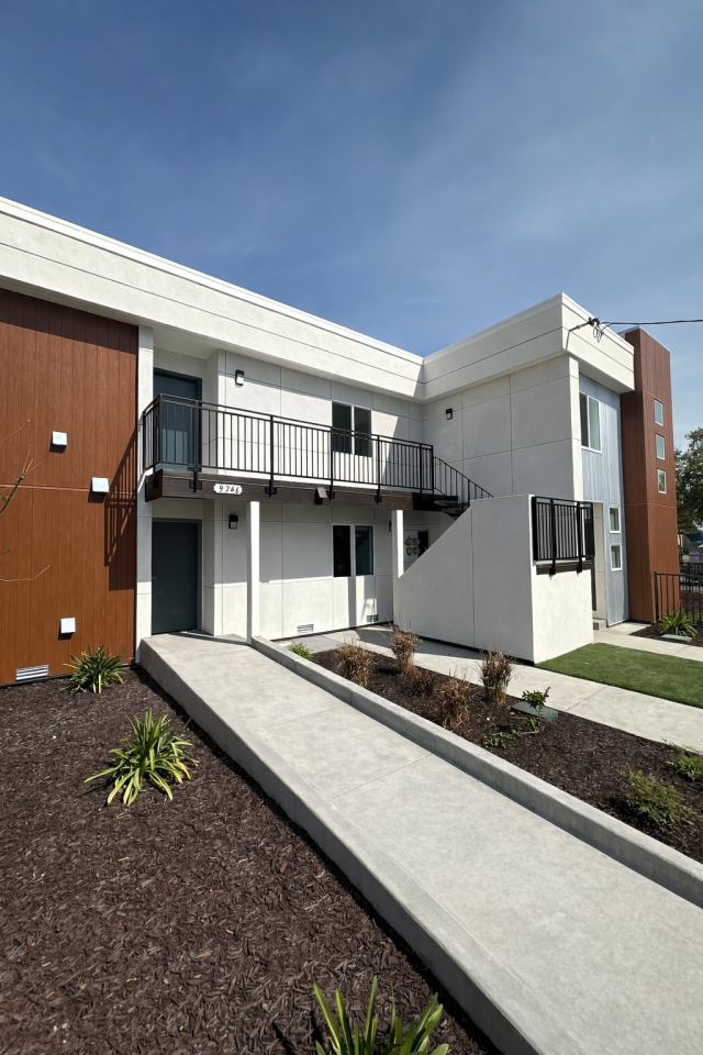 Exterior view of a renovated multi-unit residential building at 9746 Plymouth St. in Oakland after rehabilitation, featuring updated siding and a refreshed exterior.