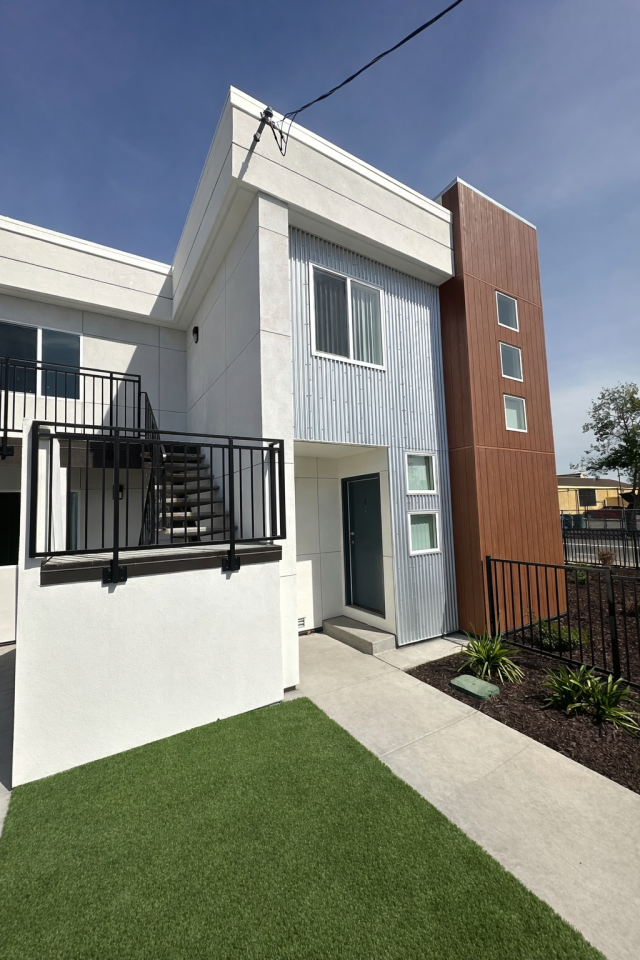 Exterior view of a renovated multi-unit residential building at 9746 Plymouth St. in Oakland after rehabilitation, featuring updated siding and a refreshed exterior.