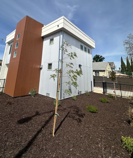 Exterior view of a renovated multi-unit residential building at 9746 Plymouth St. in Oakland after rehabilitation, featuring updated siding and a refreshed exterior.